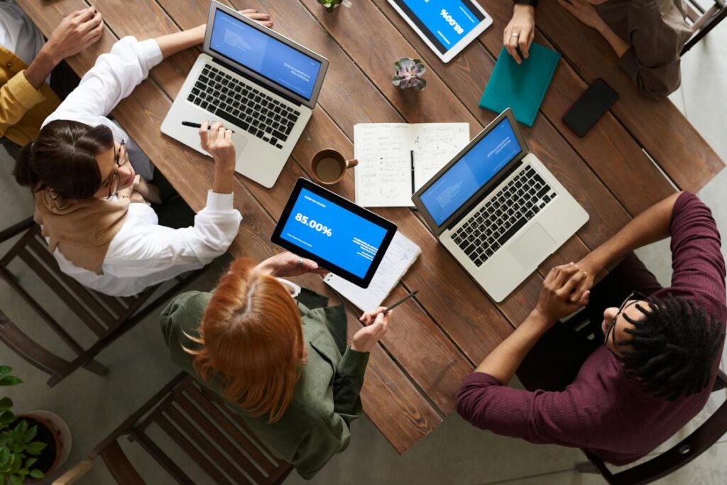 Free Top View Photo of Group of People Using Macbook While Discussing Stock Photo