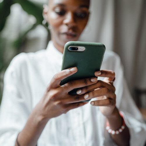 Free Black woman messaging on modern cellphone Stock Photo